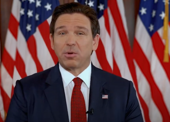 desantis speaking in front of flags