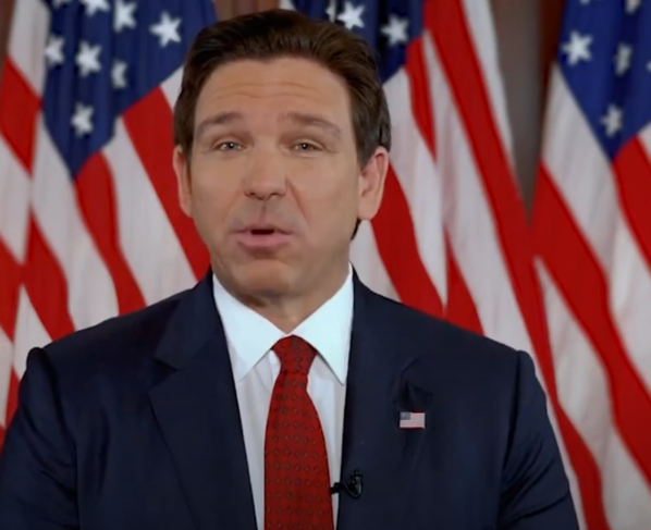 desantis speaking in front of flags