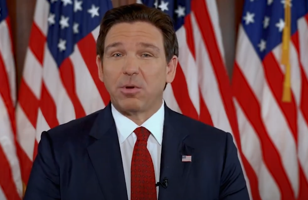 desantis speaking in front of flags